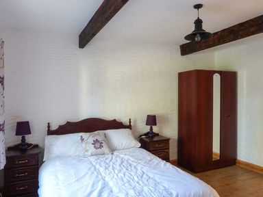 A bedroom with a bed flanked by two bedside tables with lamps and a wardrobe at The Well House in Kinvara County Galway