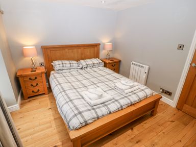 A bedroom with wooden bed frame and two bedside tables with lamps at Haddef in Nefyn