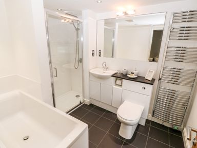 A bathroom with a bathtub shower sink toilet and heated towel rail at Haddef in Nefyn