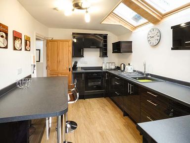 A kitchen with black cabinets a wooden door and skylight windows at High Ridge in Ambleside