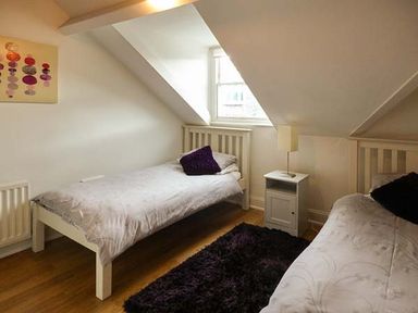 A bedroom with two single beds a nightstand with lamp and a window at High Ridge in Ambleside