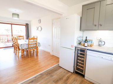 A kitchen with a refrigerator dishwasher wine cooler and dining table with six chairs at Sealyons in Fairbourne near Dolgellau