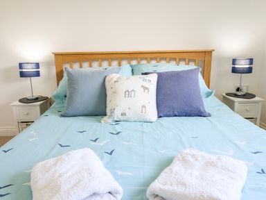 A bed with blue bedding and three pillows next to two bedside tables with blue lamps at Sealyons Fairbourne near Dolgellau