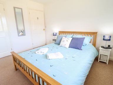 A bedroom with a wooden bed frame blue bedding and two bedside tables with lamps at Sealyons Fairbourne near Dolgellau