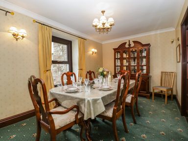 A dining room with a table set for six and a china cabinet at Moors Farm in Littledean