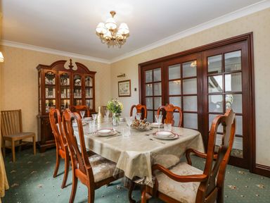 A dining room with a set table and wooden chairs at Moors Farm in Littledean