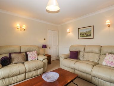 A living room with two leather sofas a wooden coffee table and wall lights at Moors Farm in Littledean