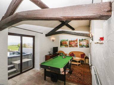 A game room with a pool table wicker chairs and a glass door leading outside at Moors Farm in Littledean