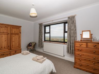 A bedroom with a bed folded towels wooden wardrobe and chest of drawers with a window view at Moors Farm in Littledean