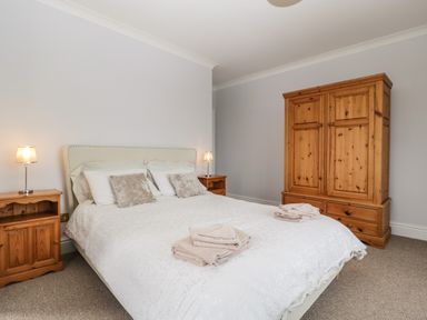 A bedroom with a double bed, two bedside tables with lamps, and a wooden wardrobe at Moors Farm in Littledean