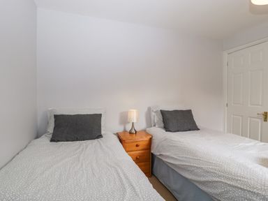A bedroom with two single beds separated by a wooden nightstand with a lamp at Moors Farm in Littledean