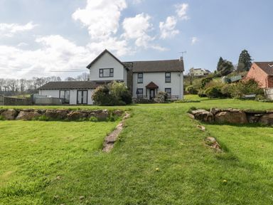 A two story white house with a lawn and stone wall in the foreground at Moors Farm in Littledean