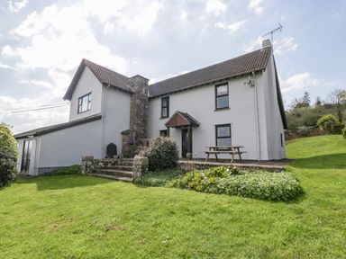 A house with a tiled roof stone chimney and surrounding lawn at Moors Farm in Littledean