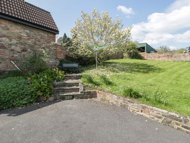 A garden with a tree a bench stone steps and a clothesline at Moors Farm in Littledean