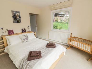 A bedroom with a bed and a wooden crib near a window at Middle Hivron in Bleddfa