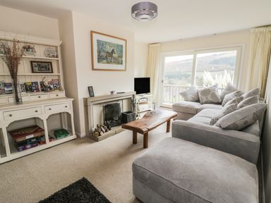 A living room with a gray sectional sofa wooden coffee table fireplace and a white cabinet with books and decorations at Middle Hivron in Bleddfa