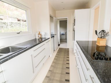 A kitchen with white cabinets black countertops a sink window belt and utensils at Middle Hivron in Bleddfa