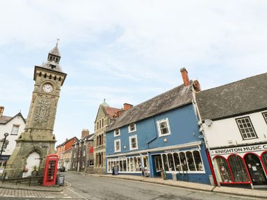 A street with a clock tower red telephone booth and shops including a blue building and Knighton Music Centre at Middle Hivron in Bleddfa