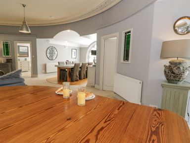 A dining area with wooden table and chairs and glasses of orange juice at Capel Mawr in Llanrug near Llanberis