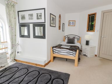 A bedroom with a single bed next to a nightstand lamp and framed pictures on the wall at Capel Mawr in Llanrug near Llanberis