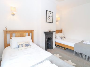 A bedroom with two beds and a fireplace at Driftwood Cottage in Heacham