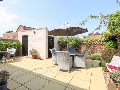 A garden with a patio set and shed at Driftwood Cottage in Heacham