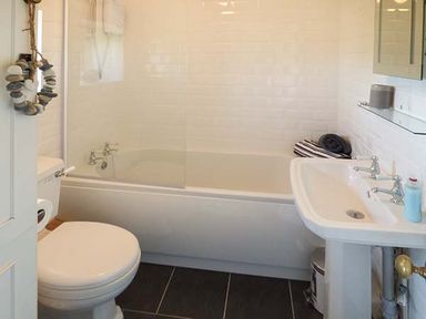 A bathroom with a toilet bathtub sink and mirror at Bwthyn Megan in Llangaffo near Newborough
