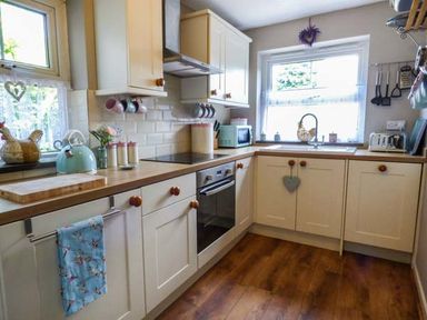 A kitchen with cream cabinets wooden countertops and kitchen appliances at Bwthyn Megan in Llangaffo near Newborough