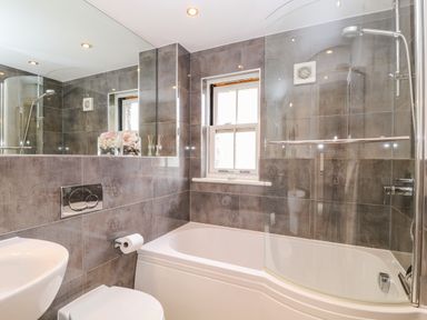 A bathroom with a bathtub shower toilet sink and window at The Creekside in Looe