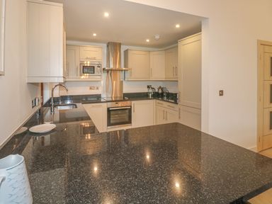 A kitchen with black granite countertops cream cabinets stainless steel appliances and a chrome faucet at The Creekside in Looe