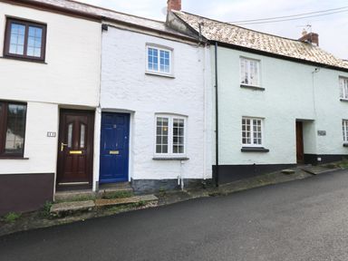A row of terraced houses with numbered doors along a paved street at 13 Castle Hill in Lostwithiel