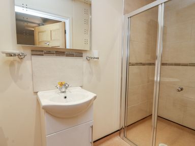 A bathroom with a sink and mirror next to a walk in shower at Caban Nant Ddu in Rhayader