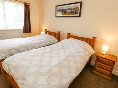 A bedroom with two single beds bedside table and lamp at Wansbeck in Longframlington near Alnwick