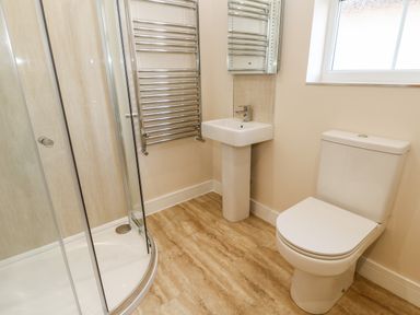 A bathroom with a corner shower cubicle a pedestal sink a toilet a heated towel rail and a window at Wansbeck in Longframlington near Alnwick