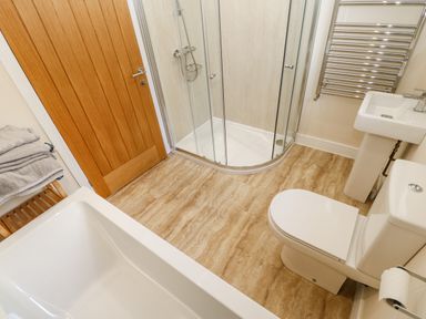 A bathroom with a bathtub shower toilet sink and wooden door at Wansbeck in Longframlington near Alnwick