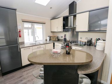 A kitchen with a countertop island a double sink stove microwave and refrigerator at 95 The Haven in Wisemans Bridge near Saundersfoot