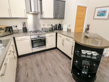 A kitchen with cream cabinets granite countertops stainless steel oven and stovetop and a curved island at 95 The Haven in Wisemans Bridge near Saundersfoot