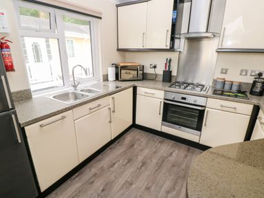 A kitchen with a double sink microwave oven gas stove countertop cabinets and wooden floor at 95 The Haven Wisemans Bridge near Saundersfoot