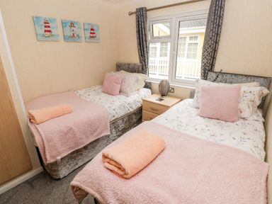 A bedroom with two single beds a nightstand and window at 95 The Haven Wisemans Bridge near Saundersfoot