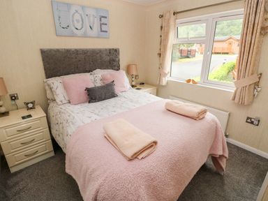 A bedroom with a double bed two nightstands and a window at 95 The Haven in Wisemans Bridge near Saundersfoot