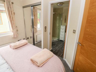 A bedroom with a bed with folded towels a mirrored closet and a door leading to a bathroom at 95 The Haven in Wisemans Bridge near Saundersfoot