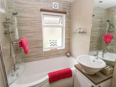A bathroom with a bathtub shower combo and a washbasin at 95 The Haven Wisemans Bridge near Saundersfoot
