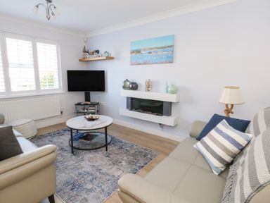 A living room with a sofa coffee table wall mounted tv and fireplace at Captains Retreat in Christchurch