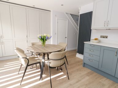 A dining area with a round table and four chairs next to kitchen cabinets and a door at Captains Retreat in Christchurch