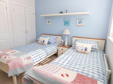 A bedroom with two single beds with blue checkered bedding and nautical themed cushions at Captains Retreat in Christchurch