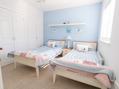 A bedroom with two single beds a nightstand with a lamp and closet doors at Captains Retreat in Christchurch