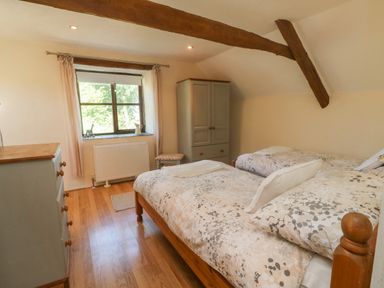 A bedroom with two single beds a wardrobe a chest of drawers a window and wooden beams at Owls Nest in South Molton
