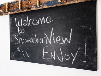 A blackboard with welcome to Snowdon View Enjoy written in chalk and a drawing of mountains at Snowdon View Harlech
