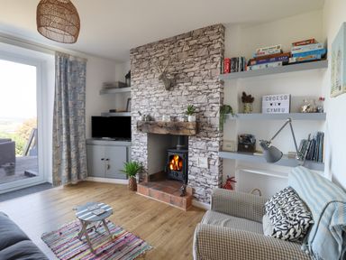 A living room with a stone fireplace television rugs and bookshelves at Snowdon View in Harlech