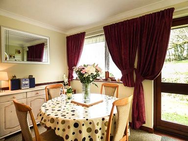 A dining area with a round table covered by a polka dot tablecloth and flowers in a vase at Chy Lowenna Rosecraddoc Holiday Village near Liskeard